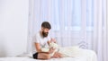 Guy on smiling face playing with teddy bear. Childhood memories concept. Man sits on bed and holds toy, white curtains Royalty Free Stock Photo