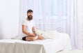 Guy on smiling face playing with teddy bear. Macho with beard and mustache relaxing with plush toy after nap. Man sits Royalty Free Stock Photo