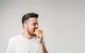 Guy is standing on the left side of the photo frame and biting an apple. This fruit is so sour that he cannot stop