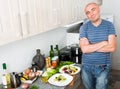 Guy stands proudly in kitchen hands clasped