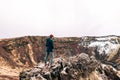 The guy stands on a rock above Lake Kerid - a crater volcanic lake in Iceland. Red volcanic soil, similar to Martian