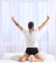 Guy stretching arms, full of energy in morning. Macho with beard stretching, relaxing after nap, rest. Good morning