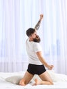 Guy stretching arms, full of energy in morning, rear view. Macho in underpants stretching, looking back and yawning. Man
