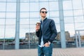 The guy in stylish sunglasses, a man walks around the city and drinking coffee from a paper Cup, a handsome guy walks around and r Royalty Free Stock Photo