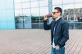 The guy in stylish sunglasses, a man walks around the city and drinking coffee from a paper Cup, a handsome guy walks around and r Royalty Free Stock Photo