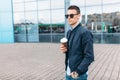 The guy in stylish sunglasses, a man walks around the city and drinking coffee from a paper Cup, a handsome guy walks around and r Royalty Free Stock Photo