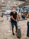 Tivat, Montenegro - 29 july 2020: A guy with a suitcase in a medical mask stands in line at the airport during the