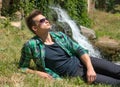 Guy in sunglasses relaxing in nature near the waterfall Royalty Free Stock Photo