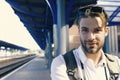 Guy with sunglasses waits for train, defocused. Missed train and travelling concept. Young man standing on platform Royalty Free Stock Photo