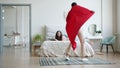 Guy in superhero costume running into room where girl reading book in bed