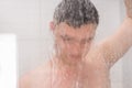 Guy taking a shower and holding shower head behind misted glass Royalty Free Stock Photo