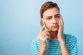 The guy is talking on the phone, upset by what he heard, on a blue background Royalty Free Stock Photo