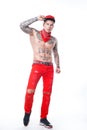 Guy with tattoos in red jeans and a cap with a red kerchief around his neck and black krasovkah