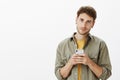 Guy thinking up answear, writing message on smartphone. Indoor shot of smart good-looking bearded male in casual outfit Royalty Free Stock Photo