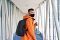 Guy tourist with a backpack and in a medical mask is walking along the airbridge from the plane to the airport terminal