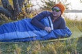 Guy tourist lies in a sleeping bag on the bank of the river. Royalty Free Stock Photo