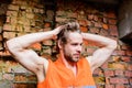 Guy tousled hair stand in front of wall made out of red bricks. Builder orange vest work construction site. Builder