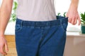 The guy trying on big jeans after losing weight. Man in oversized pants in weight loss concept Royalty Free Stock Photo