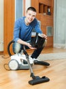 guy vacuuming with vacuum cleaner on parquet floor in living room