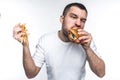 This guy is very delight of junk food. He is biting a big piece of burger and holding a full hand of french fries