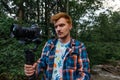 Guy a video maker with a camera on a stabilizer in his hands stands in the Greek forest and shoots video content for a travel blog