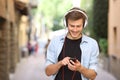 Guy walking and using a smart phone with headphones Royalty Free Stock Photo