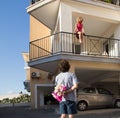 guy wants to give a bouquet of flowers to his beloved girl sitting on the balcony Royalty Free Stock Photo