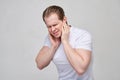 A guy in a white T-shirt massages his ears - terrible pain due to inflammation