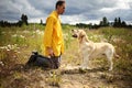 Guy in yellow jacket kissing lovely big dog during walk in filed Royalty Free Stock Photo