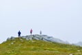 Guys stand on top surrounded by fog and low clouds near Transalpina road in Romania Royalty Free Stock Photo