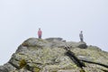 Guys stand on top surrounded by fog and low clouds near Transalpina road in Romania Royalty Free Stock Photo