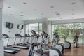 gym as an amenity within apartment towers, treadmill with televisions, exercise and ecliptic bikes, wood floors and