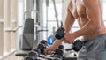 Athletic bodybuilder man lifting dumbbell from rack in gym and fitness club