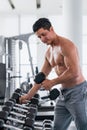 Athletic bodybuilder man lifting dumbbell from rack in gym and fitness club