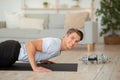 Gym at home. Smiling guy doing push-ups and looking at camera in living room interior Royalty Free Stock Photo