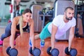 Gym man and woman push-up strength pushup with dumbbell in a workout Royalty Free Stock Photo