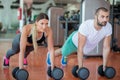 Gym man and woman push-up strength pushup with dumbbell in a workout Royalty Free Stock Photo