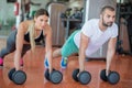 Gym man and woman push-up strength pushup with dumbbell in a workout Royalty Free Stock Photo