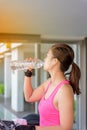 Gym woman working out drinking water by moonwalker fitness machines.