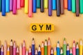 Gym word written on color cubes in frame from colorful pencils.