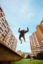 Gymnast, athlete man, young guy jumping in air, make back flip, practice Parkour in public park among high-rise Royalty Free Stock Photo