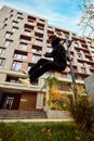 Gymnast, athlete man, young guy jumping in air, make side flip, practice Parkour in public park among high-rise Royalty Free Stock Photo