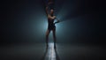Gymnast girl standing with raised hand dark space. Sportswoman posing indoors.