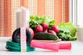 Gymnastic jump rope and vegetables for a healthy diet - tomato, cucumber, radish and lettuce are on the table near the window. On Royalty Free Stock Photo