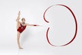 Gymnastic moves. Slender young woman in leotard doing exercises with ribbon on white background, blank space Royalty Free Stock Photo