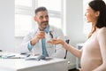 Gynaecology, medicine and pregnancy concept. Male gynecologist giving pills to smiling pregnant woman during appointment