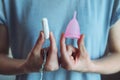 Gynecological health, menstruation products to chose, woman holding pink silicone menstrual cup and cotton tampon
