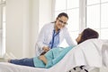 Gynecologist doctor examining heartbeat in the abdomen of pregnant woman with stethoscope. Royalty Free Stock Photo