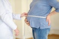 Gynecologist doctor measures with centimeter tape of a pregnant woman. Medical insurance childbearing. Family doctor for gestation