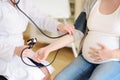 Gynecologist doctor measures the pressure of a pregnant woman. Medical insurance childbearing. Family doctor for gestation.